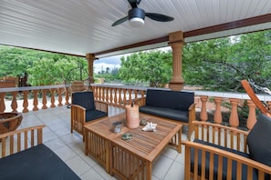A covered patio with wooden furniture, a ceiling fan, and a view of greenery. - Casa Ariba! Aruba Adventure and Explore near all… (Santa Cruz)