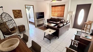 A modern living room with a sofa, coffee table, hanging chair, TV, and a ceiling fan.