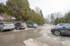 A parking lot with several cars, trees, and a stone wall in the background.