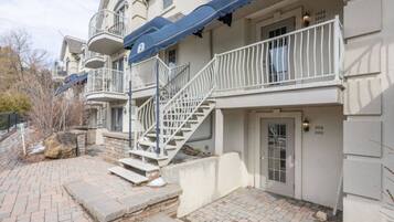 A multi-story residential building with a central staircase, a balcony, and a door with apartment numbers.