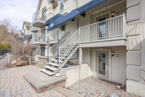 Ein mehrstöckiges Wohngebäude mit einer zentralen Treppe, einem Balkon und einer Tür mit Wohnungsnummern.