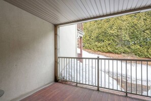 Une pièce dotée d’un plancher en bois, d’un plafond blanc et offrant une vue sur un paysage enneigé parsemé d’arbres.