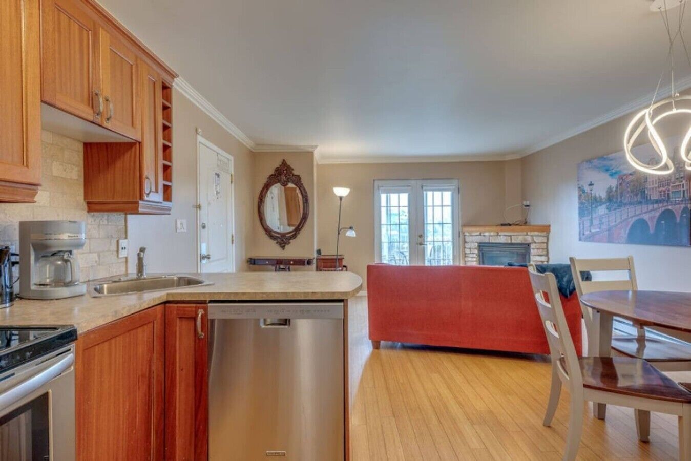 A modern kitchen with wooden cabinets, a dishwasher, and a dining area with a red bench and chairs.