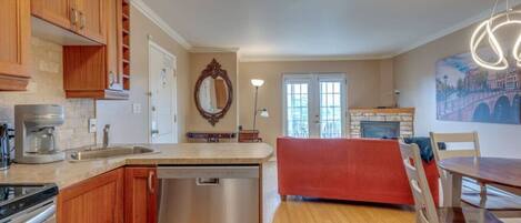A modern kitchen with wooden cabinets, a dishwasher, and a dining area with a red bench and chairs.