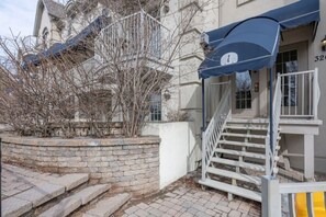 Ein Gebäude mit einer Steinsichtmauer, einer Treppe und einer blauen Markise mit der Zahl 1.