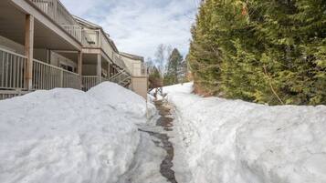 A snow-covered path leading to a building with a balcony.