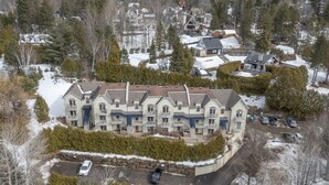 En flervåningsbostadsbyggnad med en symmetrisk fasad, flera balkonger och en parkeringsplats med plats för flera bilar.