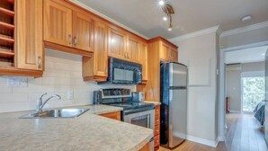 Una cocina con armarios de madera, un refrigerador de acero inoxidable, un microondas y un fregadero.