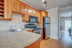 Una cocina con armarios de madera, un refrigerador de acero inoxidable, un microondas y un fregadero.