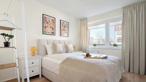 Une chambre à coucher avec un lit, des tables de chevet, une échelle et une fenêtre avec des rideaux.