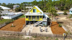 Une maison jaune avec un balcon, une véranda et une cour clôturée.