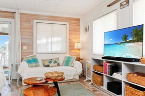 Ein gemütliches Wohnzimmer mit einer Holzverkleidung, einem weißen Sofa, einem Fernseher und einem Bücherregal.