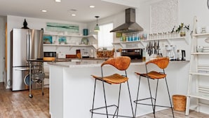 Une cuisine moderne dotée d’un îlot central, d’appareils électroménagers en acier inoxydable et de tabourets de bar.