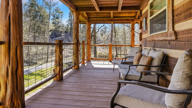 A wooden porch with a bench and a window overlooking a forested area. - Caney Creek Retreat 1 Bedroom Cabin (Cosby)