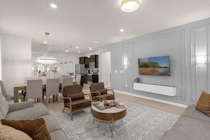 A modern living room with a dining area, a chandelier, and a painting on the wall. - 7 Bedroomss/ Windsor Cay Home (Clermont)