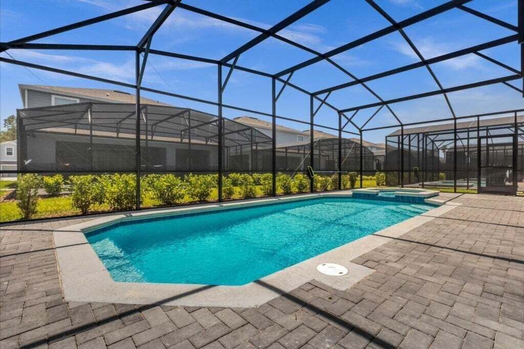 Piscina com área coberta, rodeada por um terraço de tijolos.