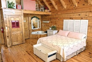 Une chambre dans un chalet en bois, avec un lit, une petite salle de bain et une armoire en bois.