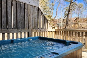 Un bain à remous avec une terrasse en bois et une clôture en bois en arrière-plan.