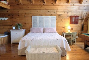 A wooden cabin bedroom with a bed, bedside table, lamp, and a small pool table. - Adorable Shut'er Inn 1 Bedroom Cabin (Pigeon Forge)