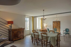 Un coin repas avec une table dressée pour quatre personnes, des chaises en bois, un lustre et un buffet en bois.