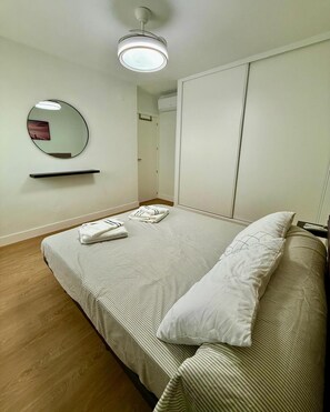 A bedroom with a bed, a bedside table, a mirror, and a ceiling light. - Front line beach Fuengirola - sea views - terrace - parking (Fuengirola)