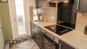 A kitchen with a built-in stove, oven, and a window with a view. - 25 Low Seaton (Workington)