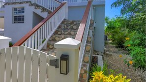 Un bâtiment à deux étages, à la façade blanche, doté d’un escalier en pierre et d’une entrée fermée par un portail.