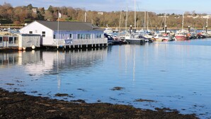A waterfront property with a dock, a building labeled 'SEAFOOD CAFE,' and several boats. - 63 Crosswinds (Bembridge)