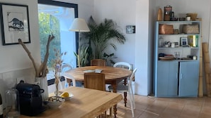 Eine Küche mit Holztisch, Stühlen, einer Kaffeemaschine und einem Schrank.