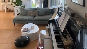 Ein Wohnzimmer mit Sofa, Klavier, Couchtisch und einem großen Fenster.