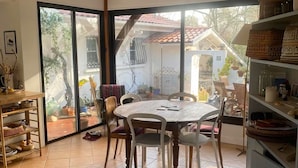 Ein Essbereich mit einem runden Tisch und Stühlen, einem Regal mit Körben und Blick durch eine Glastür auf eine Außenpatio.