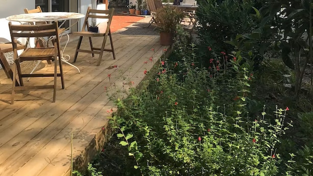 Ein Haus mit Terrasse, einem Esstisch und Stühlen sowie Topfpflanzen.