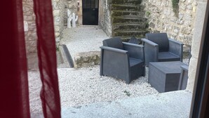 A stone building with a door labeled 'NEW YORK,' a staircase, and outdoor seating with chairs. - Authentic, charming apartment in the heart of the Ardèche (Baix)