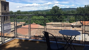 A balcony with a table and chairs, overlooking a cityscape with historic buildings and a clear sky. - Authentic, charming apartment in the heart of the Ardèche (Baix)