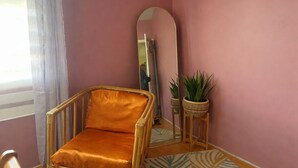 A room with a wicker chair, a mirror, and a potted plant.