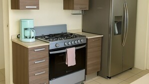 A kitchen with a stove, oven, coffee maker, and refrigerator.