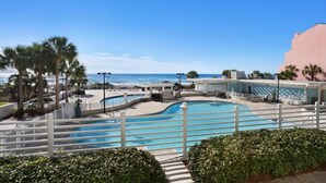 Une piscine avec vue sur l’océan, entourée de palmiers et d’une clôture blanche.