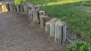 Un jardin avec une clôture en bois, un chemin de gravier et une pelouse.