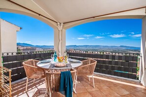 Ein Balkon mit Esstisch, der auf eine reizvolle Landschaft blickt.