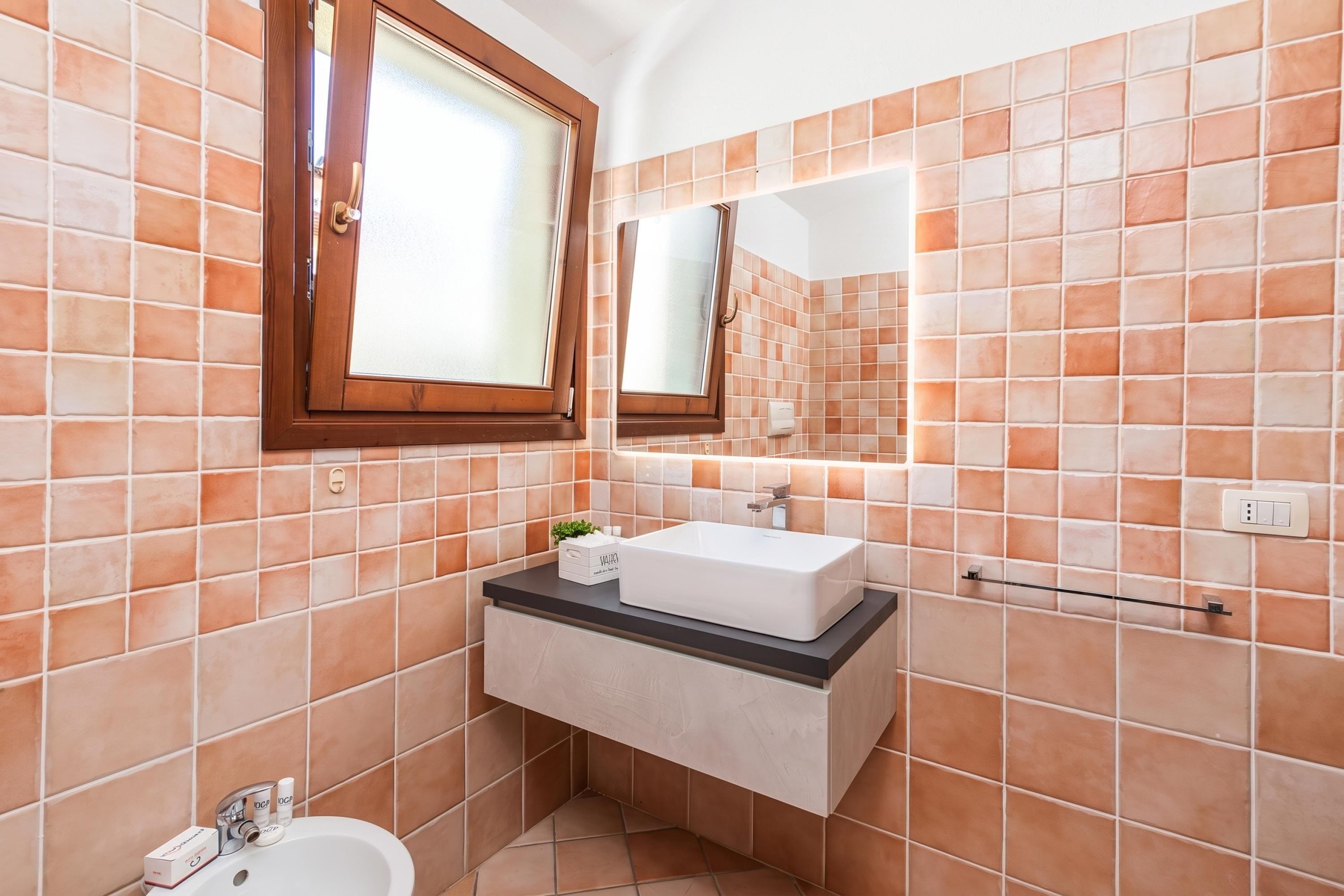 A bathroom with a white sink, a mirror, and a window.