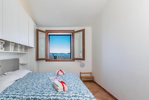 Ein Hotelzimmer mit Bett, einem Fenster mit Blick, einem kleinen Holzsessel und einem Handtuchhalter.