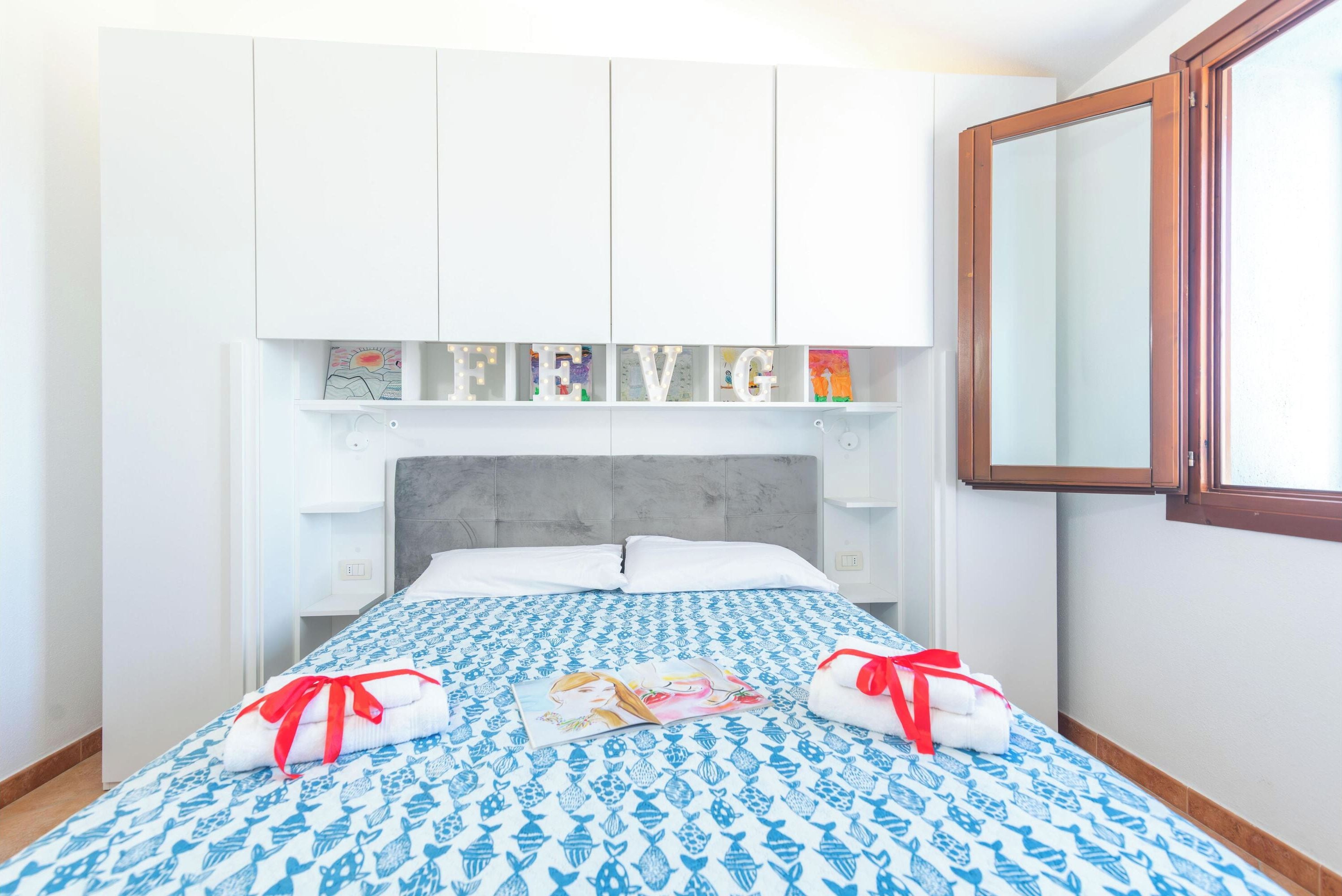 Una camera d'albergo con un letto, un'armadio bianco e uno specchio.