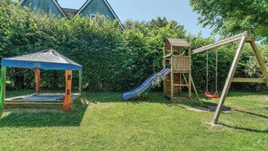 Ein Spielplatz mit Rutsche, Schaukeln und einem überdachten Spielbereich.