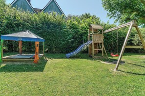 Un parque infantil con tobogán, columpios y una zona de juegos cubierta.