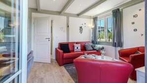 Ein modernes Wohnzimmer mit einem roten Sofa, einem Couchtisch und einem großen Fenster mit Vorhängen.