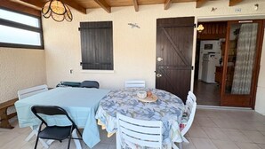 Un espace repas comprenant une table ronde, des chaises, un luminaire suspendu, une fenêtre et une porte.