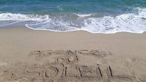 Une plage avec des vagues, et les mots « ALONG THE BEACH » et « NO SOLITARY » écrits dans le sable.