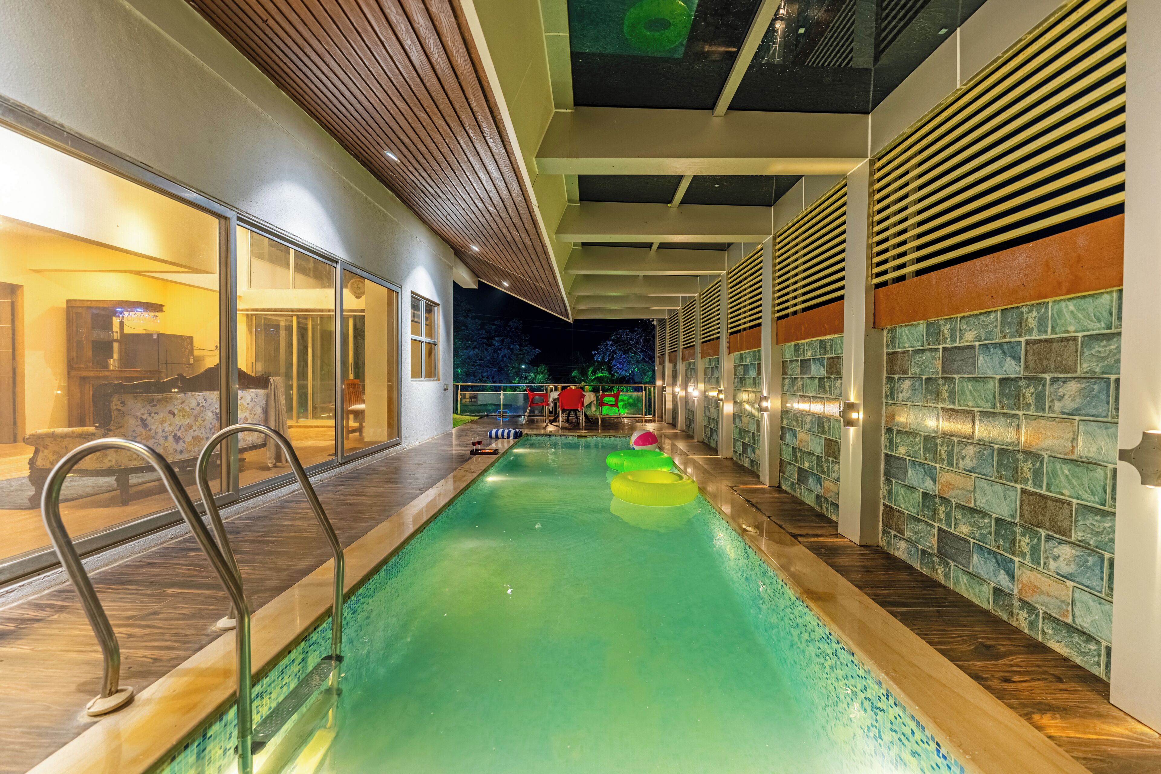 Una piscina interior con agua cristalina, cubierta de madera y paredes de azulejos.
