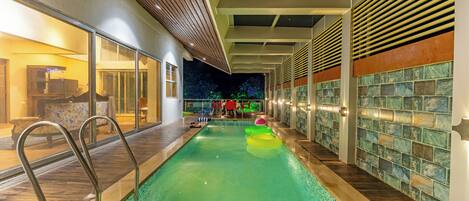 Una piscina interior con agua cristalina, cubierta de madera y paredes de azulejos.