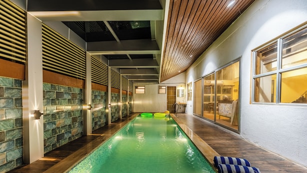 Una piscina con cubierta de madera, una toalla y una bandeja con aperitivos y bebidas.